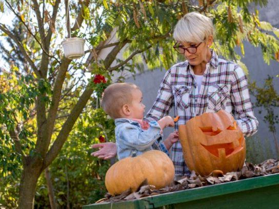 photo of grandmother with toddler working on carving a pumpkin